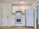 Bright kitchen features white cabinets, appliances, tile backsplash, and light wood floors at 6047 S Hill St, Littleton, CO 80120