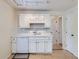 Bright kitchen features white cabinets, appliances, tile backsplash, and light wood floors at 6047 S Hill St, Littleton, CO 80120