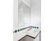Bathroom with a corner sink, white tile counters with green diamond accents, and a large mirror at 9290 Quitman St, Westminster, CO 80031