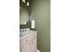 Stylish powder room with green walls, modern mirror, and vanity with gold fixtures, perfect for guests at 11825 Meadowood Ln, Parker, CO 80138