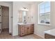 Bathroom featuring wood vanity, quartz countertop, large mirror, and an open doorway at 4729 Twelve Oaks Way, Castle Rock, CO 80104