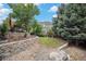 Lush backyard with terraced landscaping, mature trees, and a stone retaining wall at 11681 Night Heron Dr, Parker, CO 80134