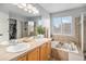 Bright bathroom featuring double sinks, a soaking tub, a separate glass-enclosed shower, and natural light at 11681 Night Heron Dr, Parker, CO 80134