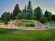 Community entrance with stone signage and lush landscaping in a tranquil, park-like setting with mature trees at 11681 Night Heron Dr, Parker, CO 80134