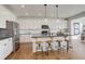 Modern kitchen featuring white cabinets, stainless steel appliances, a large island with barstool seating, and hardwood floors at 6506 Merrimack Dr, Castle Pines, CO 80108