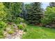 Landscaped backyard with a small stream, mature trees, and a well-maintained lawn area at 8410 S Oak St, Littleton, CO 80127