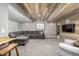 Finished basement with a rustic wood accent wall, large gray sectional sofa, and mounted television at 8410 S Oak St, Littleton, CO 80127