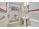 Bathroom with pedestal sink, bathtub and red and white tile at 130 S Eaton St, Lakewood, CO 80226