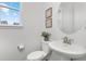 Modern bathroom features a pedestal sink, decorative mirror, and a window at 12940 Brier Ct, Firestone, CO 80504