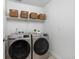 A clean laundry room with baskets on a shelf above a new silver Samsung washer and dryer set at 12940 Brier Ct, Firestone, CO 80504