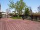 View of wooden deck with black railing overlooking backyard and lush green landscaping at 5204 S Parfet Way, Littleton, CO 80127