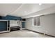 Finished basement area with carpet, window and custom shelving with blue accent wall at 5204 S Parfet Way, Littleton, CO 80127