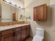 Bathroom with double sink vanity, granite countertop, wood cabinets, and wall mounted storage for convenience at 5204 S Parfet Way, Littleton, CO 80127