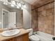 Bathroom with light wood vanity, a tub with custom tile surround, and bright lighting at 5204 S Parfet Way, Littleton, CO 80127
