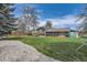Well-maintained backyard featuring a lush green lawn, mature trees, a gray home exterior, and a stone pathway at 5254 W Oberlin Dr, Denver, CO 80235