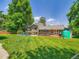 Expansive backyard with lush green grass, a wooden deck, and mature trees at 5254 W Oberlin Dr, Denver, CO 80235