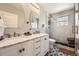 Modern bathroom features a double vanity with marble countertop and a glass-enclosed shower with bench at 5254 W Oberlin Dr, Denver, CO 80235
