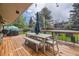 Spacious wooden deck with a dining table set, barbecue, string lights, and a view of the landscaped backyard at 5254 W Oberlin Dr, Denver, CO 80235