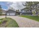 Inviting exterior features a well-maintained lawn, charming landscaping, and a brick driveway leading to the home's entrance and garage at 5254 W Oberlin Dr, Denver, CO 80235