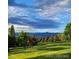 Scenic view of a golf course with mature trees and mountains in the background under cloudy sky at 5254 W Oberlin Dr, Denver, CO 80235
