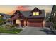 Charming home exterior at dusk with a well-manicured lawn, a covered porch, and a two-car garage at 18009 E 47Th Pl, Denver, CO 80249