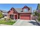 Charming red two-story home with a well-manicured lawn, beautiful landscaping, and a two-car garage at 18009 E 47Th Pl, Denver, CO 80249