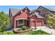 Stylish red two-story home featuring beautiful landscaping and a convenient two-car garage at 18009 E 47Th Pl, Denver, CO 80249