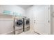 Bright laundry room with stainless steel washer and dryer, tiled floor, and storage shelf at 18009 E 47Th Pl, Denver, CO 80249