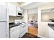 Galley kitchen featuring white appliances and cabinets adjacent to a living room with warm, neutral color palette at 3050 W 32Nd Ave # 202C, Denver, CO 80211