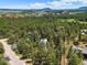 Stunning aerial view of a house nestled in a serene forest with beautiful mountain scenery in the background at 6100 Apache Dr, Larkspur, CO 80118