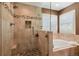 Bathroom with stone-tiled shower and tub surrounded by travertine at 19653 E Ida Dr, Aurora, CO 80015
