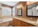 Bathroom with dual sinks, granite countertops, tub, and window shutters at 19653 E Ida Dr, Aurora, CO 80015