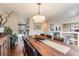 A dining room with a long wooden table, seating for six, and natural light with an open view to the kitchen at 1166 Krameria St, Denver, CO 80220
