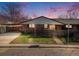 Charming brick home featuring a well-maintained lawn and a unique, modern privacy fence and covered car port at 1166 Krameria St, Denver, CO 80220