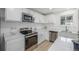 Bright kitchen features stainless steel appliances, white cabinets, quartz countertops, and wood-look flooring at 2232 Coronado Pkwy # B, Denver, CO 80229