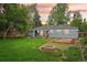 Spacious backyard with green lawn, fire pit, and a small deck with outdoor seating under a colorful sky at 5445 Nebraska Way, Denver, CO 80246