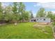Expansive backyard with lush green grass, mature trees, fire pit, and inviting deck for relaxation at 5445 Nebraska Way, Denver, CO 80246