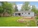 Spacious backyard with green lawn, fire pit, and a small deck with outdoor seating under a colorful sky at 5445 Nebraska Way, Denver, CO 80246