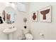 Cozy powder room featuring a pedestal sink, a round mirror, and natural light from a window at 9855 Biscay St, Commerce City, CO 80022
