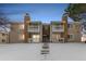 Tan two-story condo building with snow-covered front yard and steps at 14191 E Jewell Ave # 203, Aurora, CO 80012