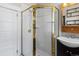 Bathroom featuring a glass shower with gold trim, a modern sink, and a vanity with built in shelving at 458 Cherry St, Hudson, CO 80642
