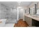 Bathroom featuring a glass shower, soaking tub, wood floors, and updated vanity at 6625 E 6Th Avenue Pkwy, Denver, CO 80220