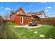 Large backyard featuring a brick house, stone patio, grassy area, and a grill at 3632 N Marion St, Denver, CO 80205