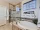 Bathroom with soaking tub, tile surround, glass enclosed shower and bright window at 16658 Prospect Ln, Broomfield, CO 80023