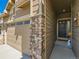 A welcoming front door is flanked by a stone pillar, a black front door, and neutral siding at 16658 Prospect Ln, Broomfield, CO 80023