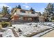 Ranch style home with snow-covered yard, attached garage, and landscaping at 14022 W Alaska Dr, Lakewood, CO 80228