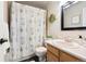 Traditional bathroom featuring a tub with leaf-patterned shower curtain, a wooden vanity, and tiled walls at 713 Aspen Rd, Golden, CO 80401