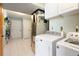 Bright laundry room features white tile floors, white cabinets, modern washer and dryer units, and closet storage at 713 Aspen Rd, Golden, CO 80401