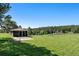 Quaint outbuilding with barn doors and concrete apron sits on a lush green lawn surrounded by evergreen trees at 713 Aspen Rd, Golden, CO 80401
