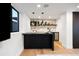 Basement wet bar with dark cabinets, a light marble backsplash, and shelves at 220 Glencoe St, Denver, CO 80220